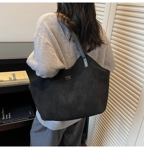 Model wearing a black quilted tote bag with silver clasp in a cozy indoor library setting