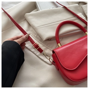 Vue détaillée du sac à main rouge montrant les ferrures dorées et la texture du cuir
