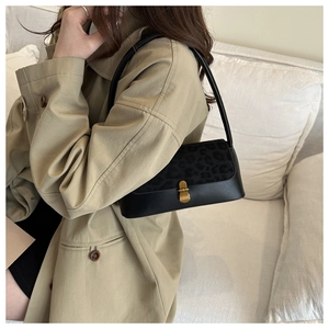 Detail of vintage baguette bag featuring leopard print flap and gold clasp on trench coat