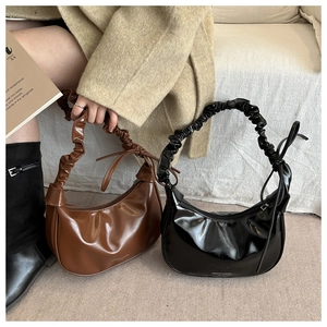 Macro detail of pleated handle and crescent shoulder bag in brown and black leather