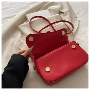 Détail du sac à main en similicuir rouge avec quatre boutons pression magnétiques dorés