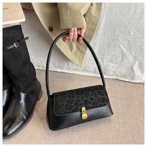 Detail of leopard print flap and vintage gold buckle on a black leather underarm bag