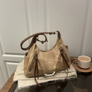 Brown suede crescent tote bag with pearl chain detail on a cozy lifestyle background