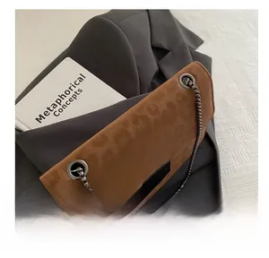 Vue détaillée du sac carré en daim marron avec bandoulière chaîne sur un blazer