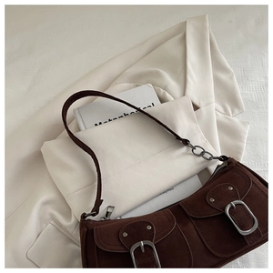 Detailed view of dark brown faux suede shoulder bag with metallic buckles and rivets