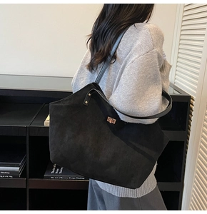 Detail of a large black tote bag with matte texture and elegant metal twist lock closure