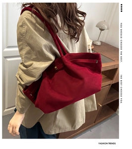 Side view of red suede tote bag showing wing-shaped pleats and metal buckle details