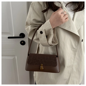 Detail view of brown leather shoulder bag featuring vintage leopard print flap and brass lock
