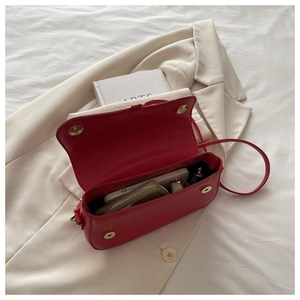 Détail de l'intérieur d'un sac rouge en PU avec objets quotidiens sur blazer blanc