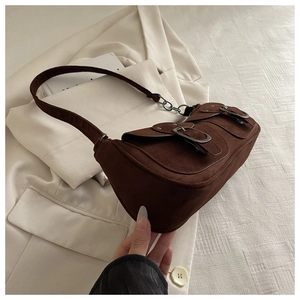 Detailed macro view of vintage brown suede shoulder bag with retro bronze buckle pockets