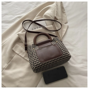 Detail of houndstooth crossbody bag with brown leather strap on beige suit jacket