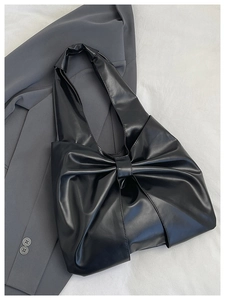 Détail du sac à main en similicuir noir avec motif gros nœud et texture plissée élégante