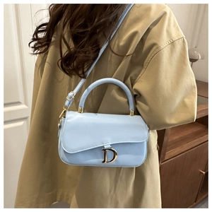 Détail du sac selle bleu clair avec boucle en D dorée et bandoulière réglable