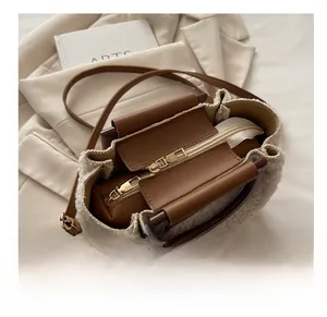 Detail view of white teddy fur shoulder bag with brown leather handles and zipper