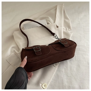 Detail of dark brown suede baguette bag with metal buckles and vintage chain strap