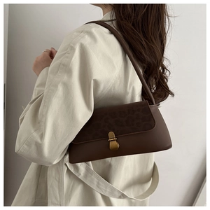 Close-up of vintage brown baguette bag with leopard print flap and gold clasp detail