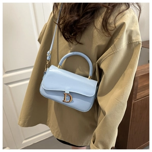 Gros plan du sac à main en cuir bleu clair avec fermoir en D doré et bandoulière réglable