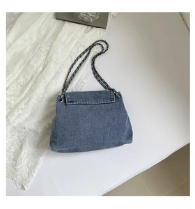 Close-up of blue denim fabric texture and metallic chain strap on a tote bag