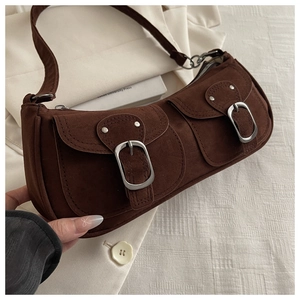 Detail of brown faux suede shoulder bag featuring twin front pockets and silver buckles