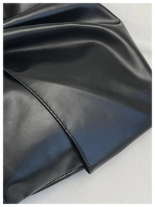 Détail du cuir noir avec plis souples et design de nœud élégant sur le sac à main