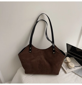 Détail d'un sac cabas en daim matelassé marron foncé avec rivets dorés élégants