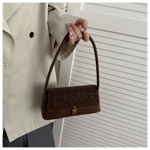 Detail of vintage leopard print flap and gold lock on a brown leather shoulder bag