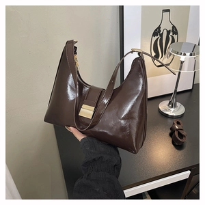 Detail of glossy chocolate brown crescent bag with gold hardware and dual straps