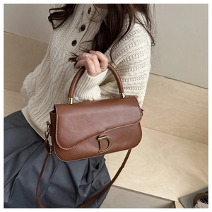 Détail du sac à main marron caramel avec boucle D dorée sur sac à bandoulière en cuir
