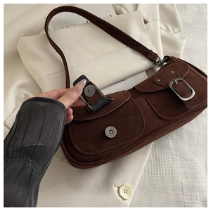 Detail of vintage brown suede shoulder bag featuring double front pockets and metal buckles