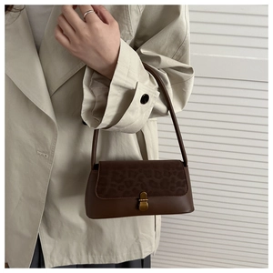 Detail of vintage leopard print flap and bronze metal buckle on the brown shoulder bag