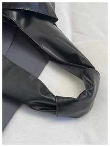 Détail de la poignée d'un sac à main en cuir noir avec plis souples et coutures premium