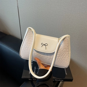 White faux leather crescent shoulder bag with silver bow accent and crocodile texture