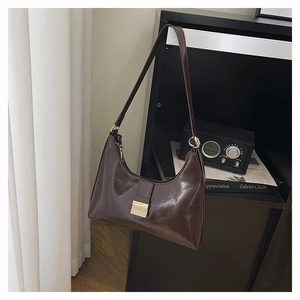 Detailed view of dark brown high-gloss leather hobo bag with gold metal buckle