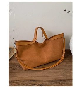 Detail of caramel suede tote bag featuring smooth leather handles and a long shoulder strap