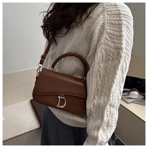 Sac à main vintage en cuir marron avec pendentif D doré porté sur un mannequin