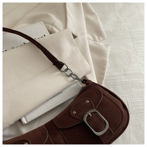 Detail of dark brown suede shoulder bag with retro buckle and metal rivet accents
