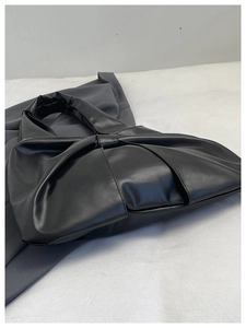 Détail du sac à main noir en similicuir avec design esthétique de nœud papillon plissé