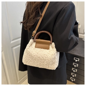 Detail of plush cream faux fur handbag featuring round wood-style handles and leather flap