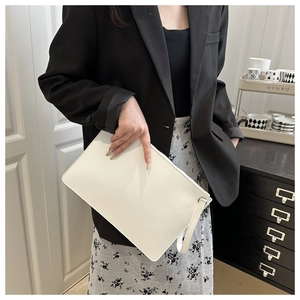 Minimalist white envelope clutch bag with wrist strap shown in a modern home lifestyle setting