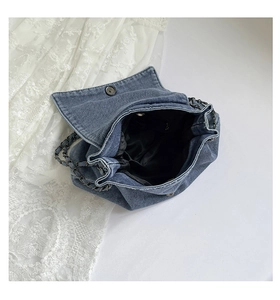 Detail of blue denim tote bag with chain strap and spacious interior compartment