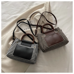 Detail of houndstooth plaid handbag with wooden ring handle and leather front pocket