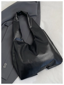 Détail du sac à bandoulière en cuir PU noir avec nœud papillon sur un blazer gris