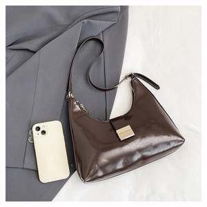 Detail view of glossy dark brown hobo bag with gold hardware on textured fabric