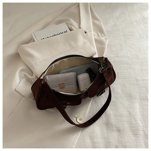 Detail view of brown suede shoulder bag interior showing daily essentials and zip pocket