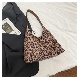 Détail du sac hobo avec imprimé léopard et bandoulière en cuir marron sur tissu blanc