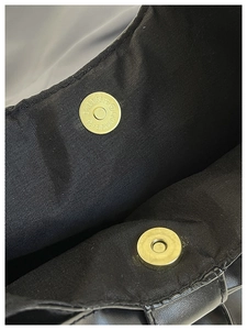 Vue détaillée des fermoirs magnétiques dorés sur un sac à main noir minimaliste
