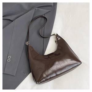 Top-down view of glossy dark coffee crescent bag with retro gold hardware and magnetic flap