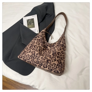 Détail du sac cabas à imprimé léopard avec bandoulière en cuir sur fond blanc doux