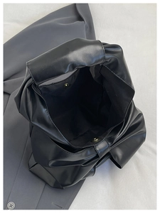 Vue détaillée du sac bandoulière noir avec boucle magnétique et cuir synthétique souple