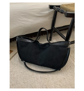 Detailed close-up of large black matte tote bag with leather straps on a soft rug